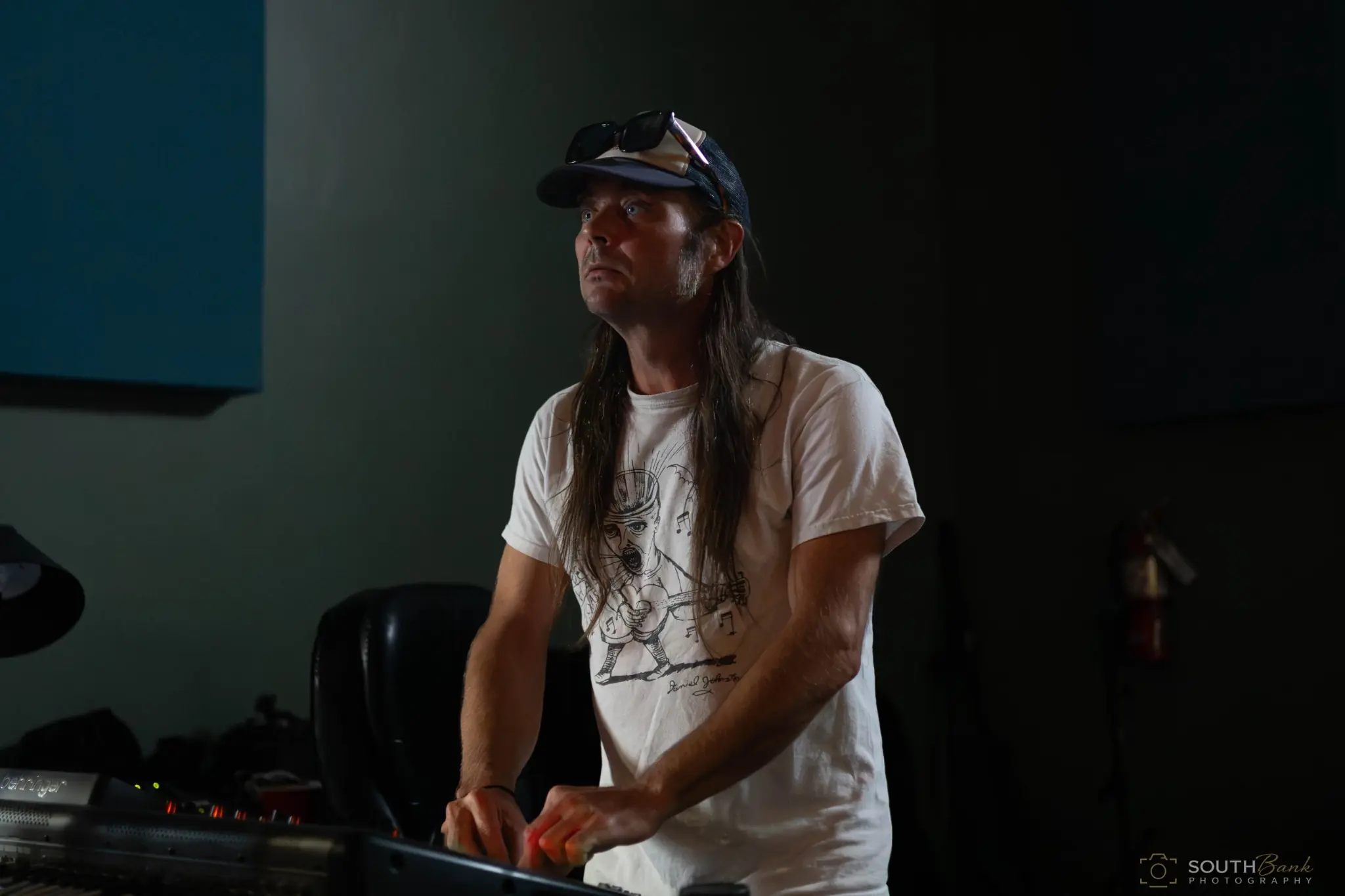 Long-haired musician at a keyboard during a low-lit performance