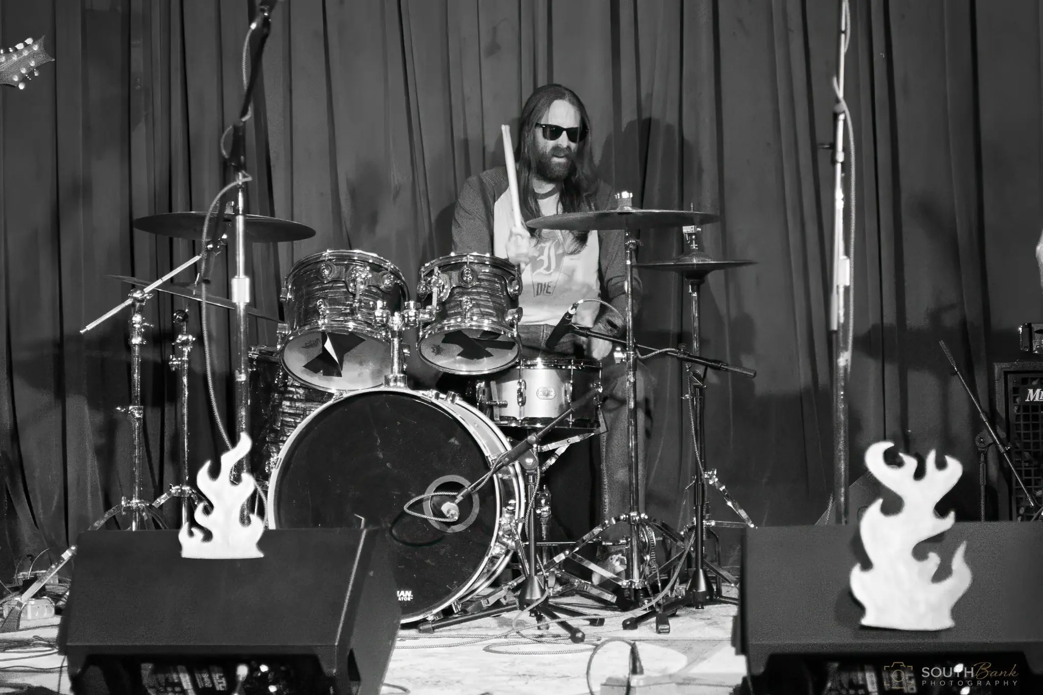 Drummer performing behind a full kit in black and white