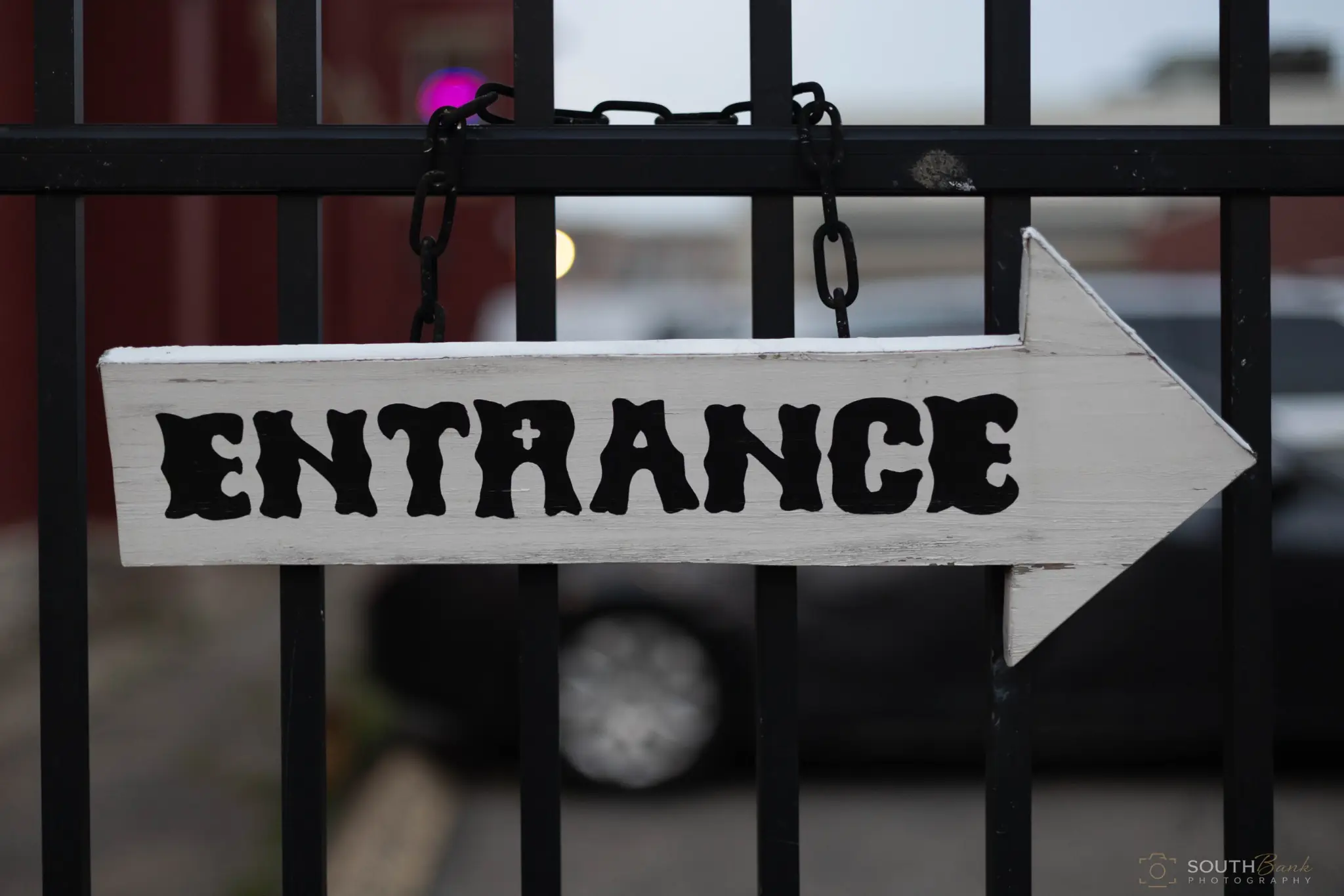 Hand-painted entrance arrow hanging on a venue gate