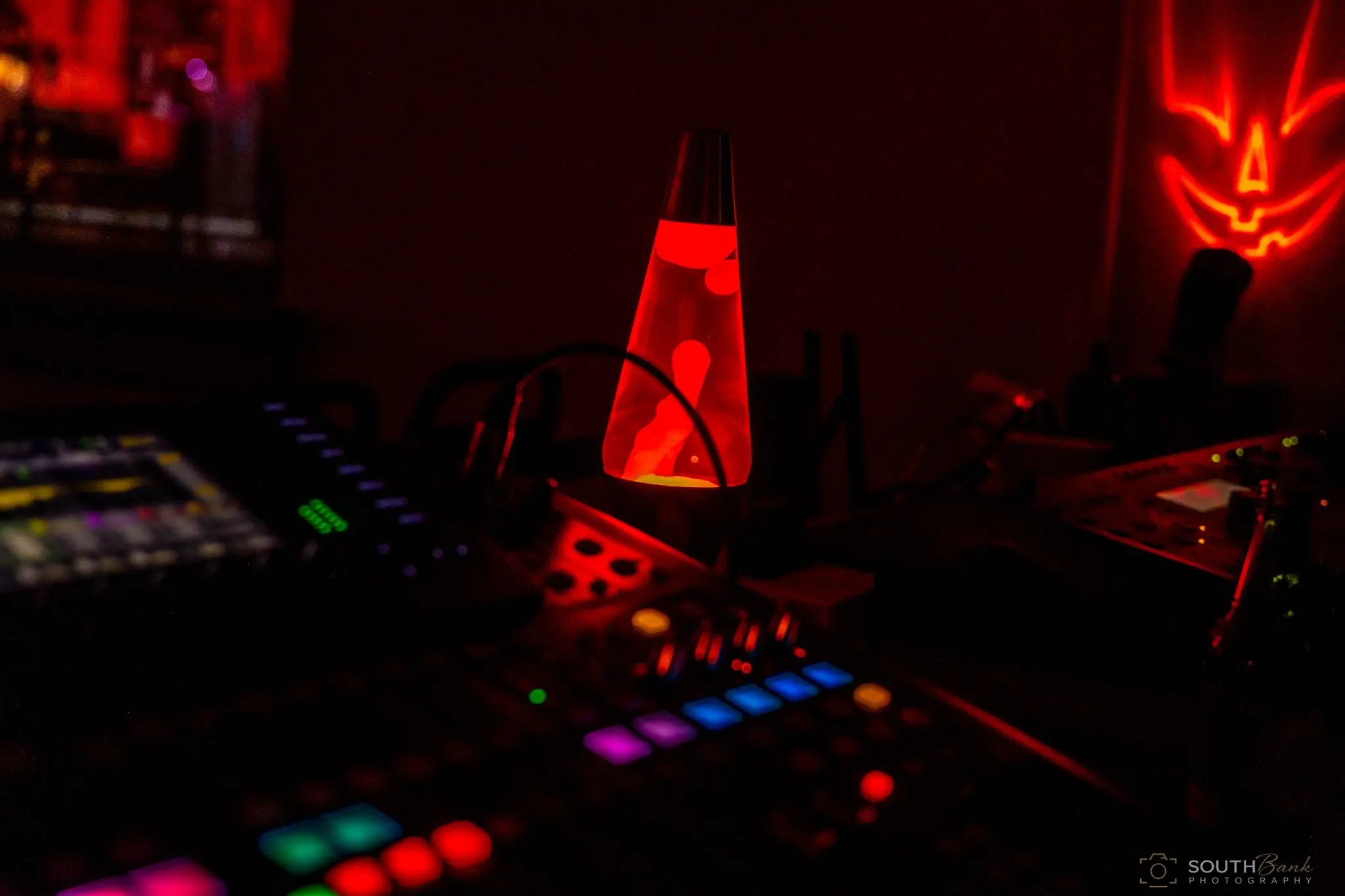 Red lava lamp glowing beside audio equipment in a dark venue