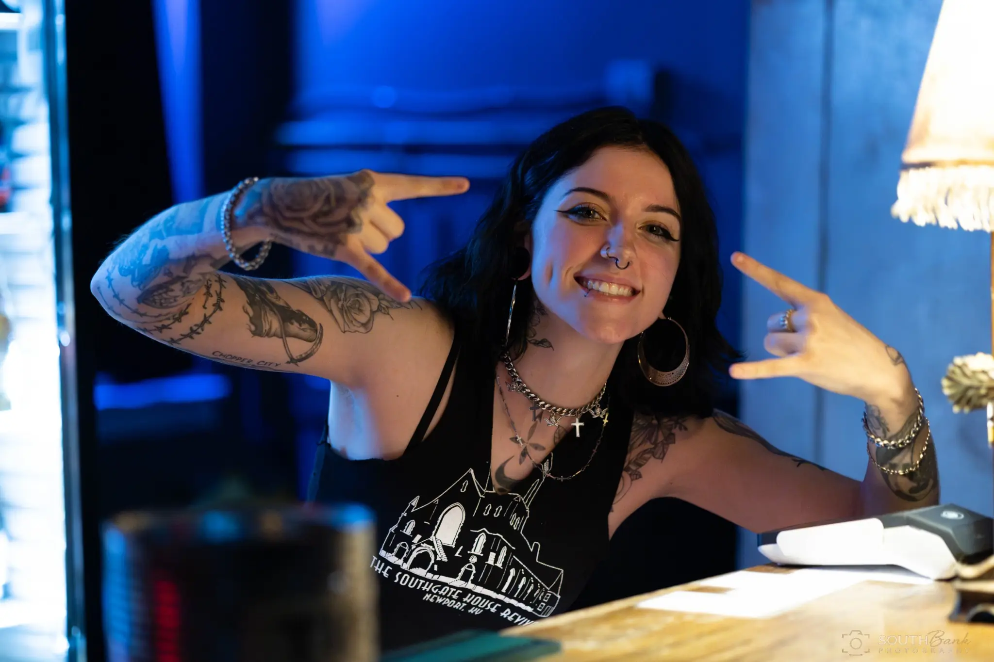 Tattooed venue team member smiling beneath blue light
