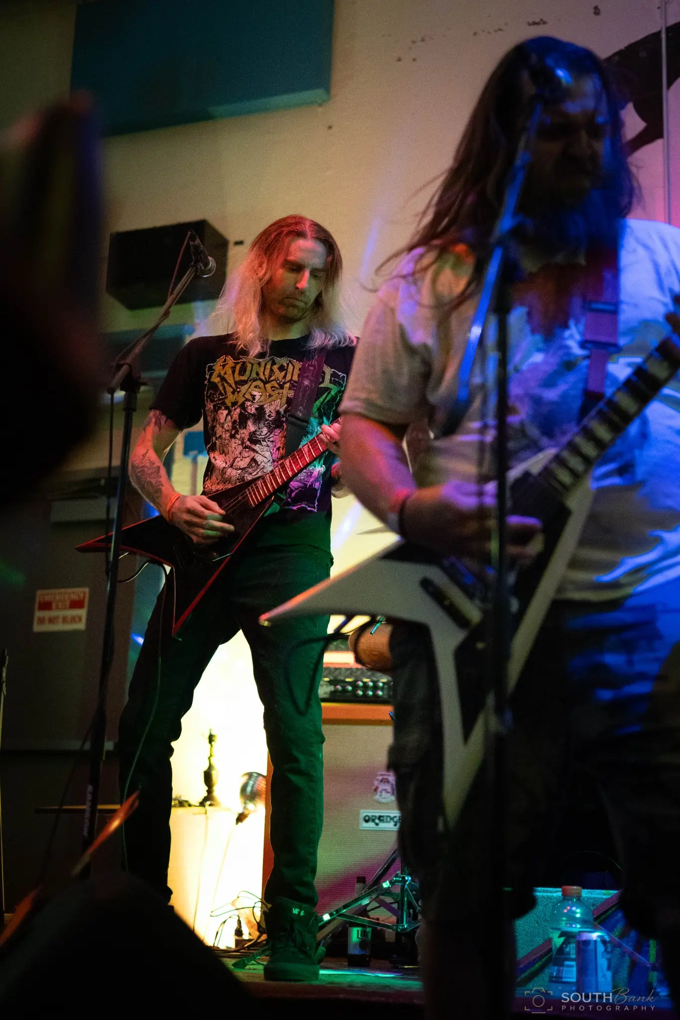 Two guitarists sharing the stage under blue and amber lighting